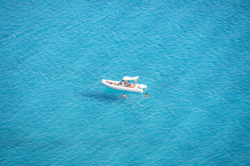 The beautiful view from the Porto Giunco ​​tower overlooking the Gulf of Villasimius with blue sea and boats that seem to fly and a girl admiring it