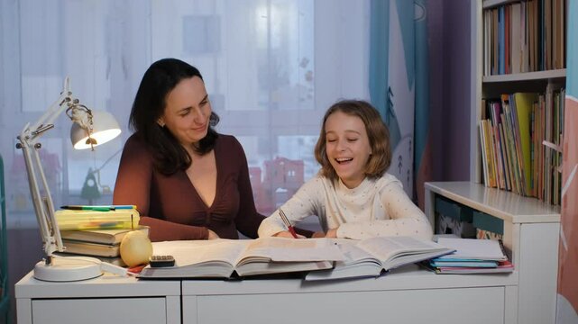 In a cozy evening setting, a mother guides her young daughter through homework. They share smiles and laughter, surrounded by books and study materials, slow motion