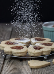 Homemade cookies on wooden table that are sprinkling with icing sugar