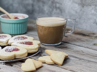 A plate of cookies and a mug of coffee sit on a wooden table
