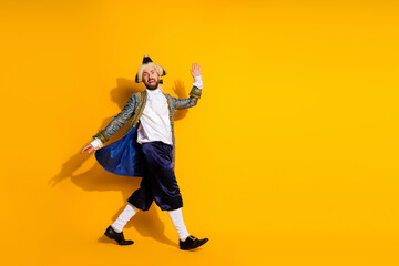 Playful young man in vintage nobleman costume posing against vibrant yellow background