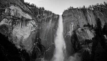 Fototapeta premium Majestic waterfall cascading down sheer granite cliffs. Breathtaking monochrome landscape.