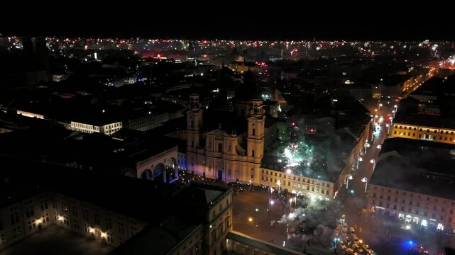 Aerial shot at midnight of fireworks and firecrackers lighting up downtown Munich, Germany, Odeonplatz. Feldherrnhalle and Theatinerkirche stand as part of festive scene. Silvester Feuerwerk Muenchen