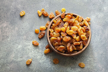 Dried grapes in wooden bowl or scoop on rustic background, healthy dry fruit concept, raisins