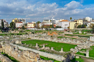 Obraz premium Kerameikos archaeological site in Athens, Greece, showcasing ancient ruins surrounded by modern urban buildings under a partly cloudy sky