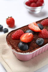 Delicious tiramisu cake with berries on table