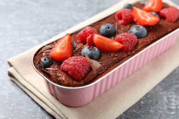 Delicious tiramisu cake with berries on table