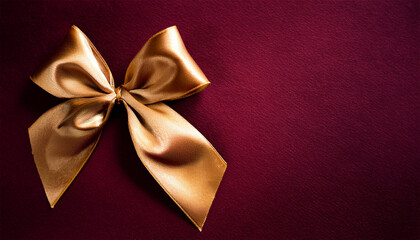 golden satin bow on maroon background top view