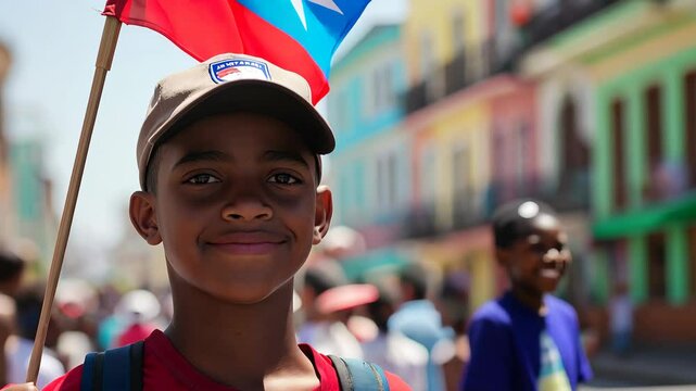 Portrait of a young boy holding a Cuban flag during a street celebration with colorful buildings in the background