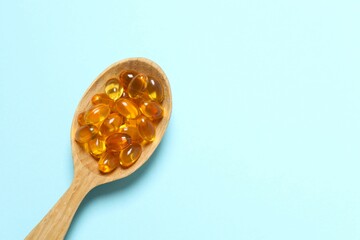 Capsule of omega 3, 6, 9 fish oil, vitamin, food supplement in wooden spoon on color background 