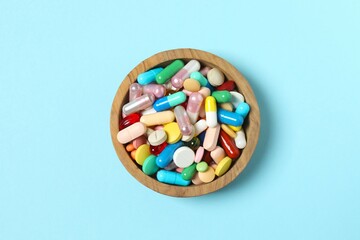 Various pills in a bowl on color background