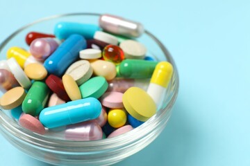Various pills in a bowl on color background