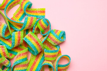 Tasty rainbow sour belts on pink background, top view. Space for text