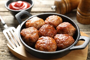 Tasty meatballs in baking dish served on wooden table, closeup