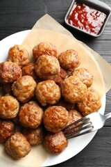 Many delicious meatballs served with ketchup on dark wooden table, flat lay