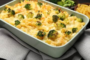 Tasty pasta casserole with cheese and broccoli in baking dish on table, closeup
