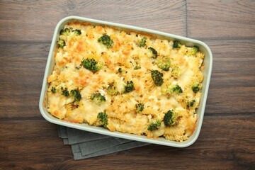 Tasty pasta casserole with cheese and broccoli in baking dish on wooden table, top view