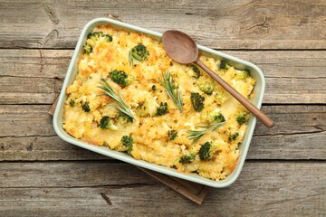 Tasty pasta casserole with cheese, rosemary and broccoli in baking dish on wooden table, top view