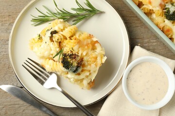 Tasty pasta casserole with cheese and broccoli served on wooden table, flat lay