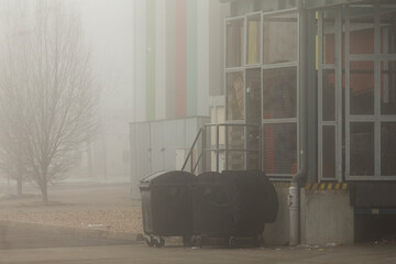 In a fogcovered urban environment, strategically situated trash bins are positioned adjacent to a...