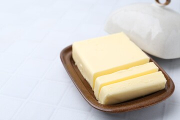Cut tasty butter in dish on light grey table, closeup. Space for text