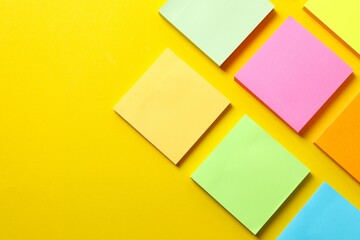 Top view of stack of colorful sticky notes on yellow background