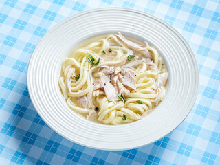 chicken noodle soup with herbs in a white bowl