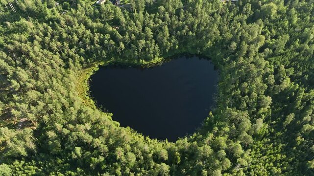 Aerial footage of the heart-shaped Nackern Lake surrounded by dense vegetation in Bestorp, Sweden