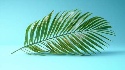 Fototapeta premium Single vibrant green palm frond on blue background.
