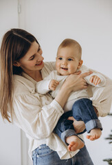 Mother holding her baby smiling near Christmas tree