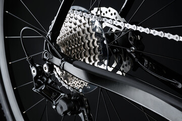 Shifting gears on rear transmission of bicycle on black background. Rear derailleur, cassette and chain.