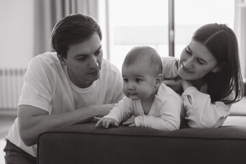 Happy family looking their baby crawling on sofa