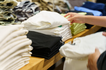 Organizing folded shirts on a wooden table in a retail store environment