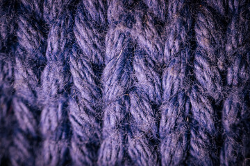 A macro view of dark blue knitted fabric showcasing the rich texture and thick yarn weave. The soft and intricate fibers highlight the cozy and durable material.