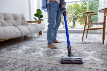 Man cleaning rug with cordless vacuum cleaner at home, closeup