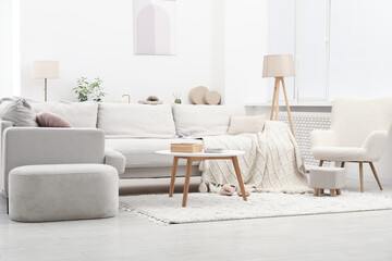 Light living room interior. Comfortable sofa with blanket and other furniture indoors