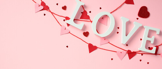 Valentines Day sign Love, red and pink heart bunting, gift box, and confetti on pink background. Love, romance concept.