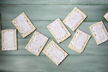 Many delicious strawberry or cherry tarts ready to pop in the toaster for a treat or breakfast over a green wood background. Table top view.