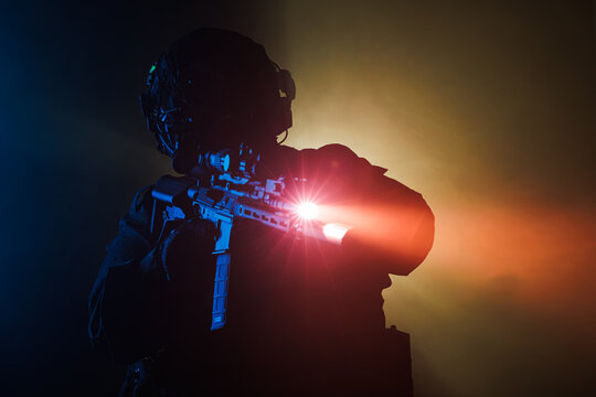 Armed tactical soldier aiming rifle with flashlight on colorful background