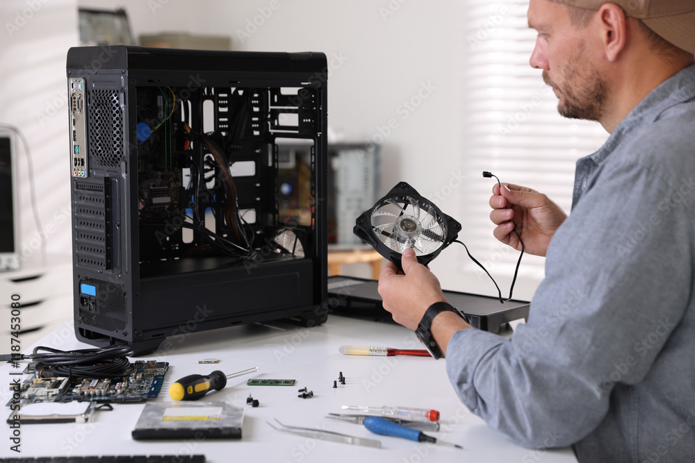 Poster man installing fan into computer at white table