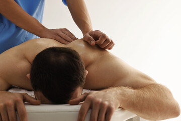 Professional physiotherapist doing back massage for his client indoors, closeup