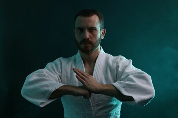 Karate fighter wearing uniform in color lights and smoke