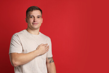 Man making promise on red background, space for text. Oath gesture
