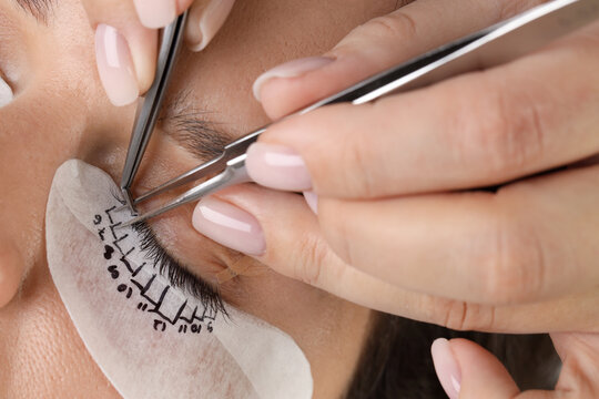 Young woman undergoing lash extensions procedure, closeup