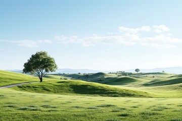 Obraz premium Rolling green hills under a clear blue sky with a solitary tree standing out in the landscape during daylight
