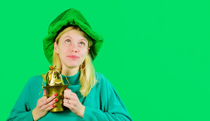 Patrick's Day girl with pot of gold. Cute young woman in green leprechaun hat with little bag of...