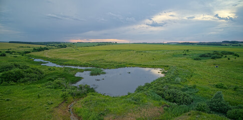 Large body of water is surrounded by a lush green field