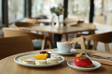 Delicious cottage cheese pancakes, dessert and coffee served on wooden table in cafe