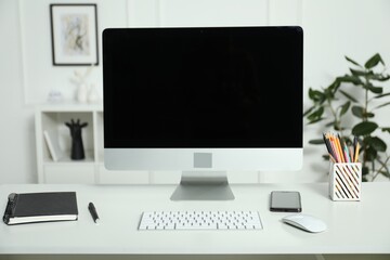 Fototapeta premium Modern workplace with computer and stationery on white desk indoors
