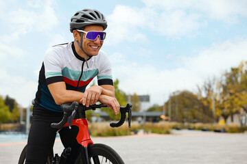 Athletic man with helmet and bicycle outdoors, space for text